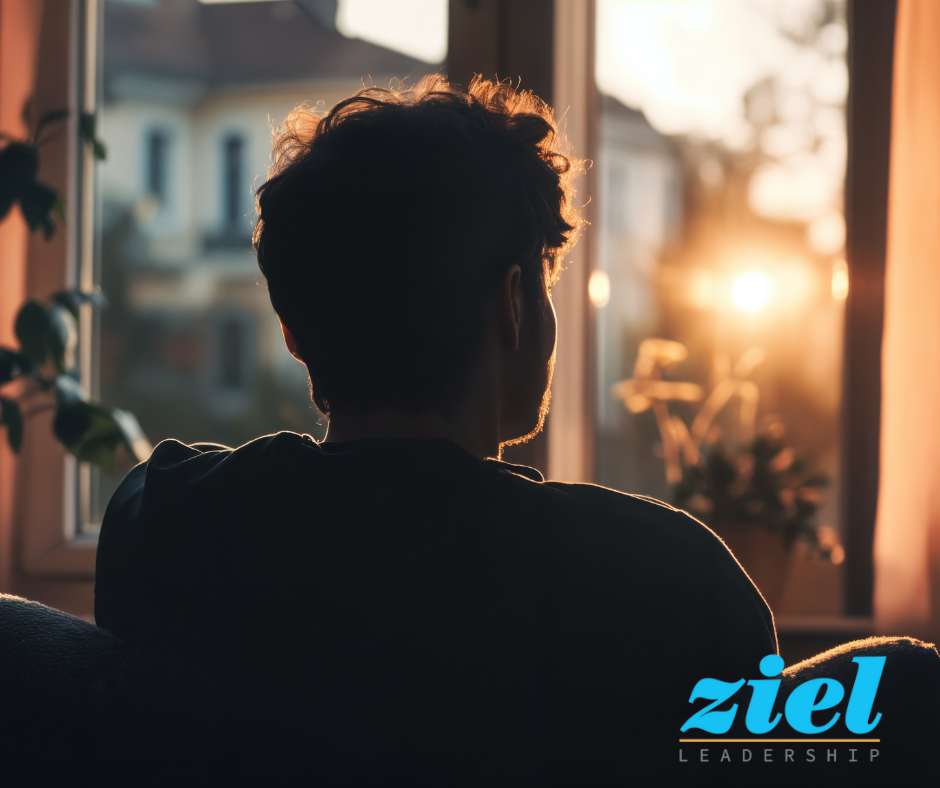 Professional sitting by window in natural sunlight, taking time to reflect